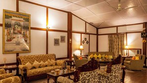 A traditional living room with a sofa, armchairs, a coffee table, and a painting on the wall. - amã Stays & Trails Hathikuli, Assam (Bokakhat)