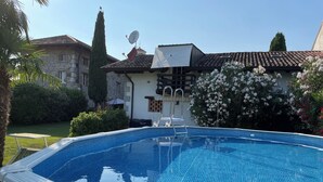 A swimming pool with a tiled deck, a lounge chair, and a small table. - Residence San Bernardo - Ap. "San Bernardo" - 6 km from the center of Udine (Udine)