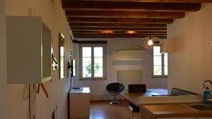 A kitchen with wooden beams, a dining area with a chair, and a window providing natural light. - Residence San Bernardo - Ap. "San Bernardo" - 6 km from the center of Udine (Udine)