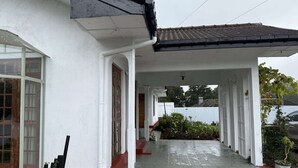 A covered walkway leading to a building with a white exterior and red steps. - Cottage 88 (Nuwara Eliya)