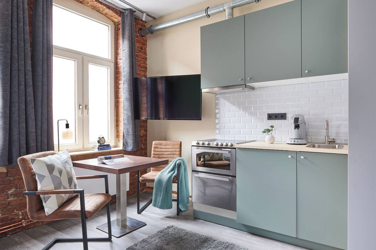 A modern kitchen with a built-in oven, a flat-screen TV, and a dining area with a table and chairs.