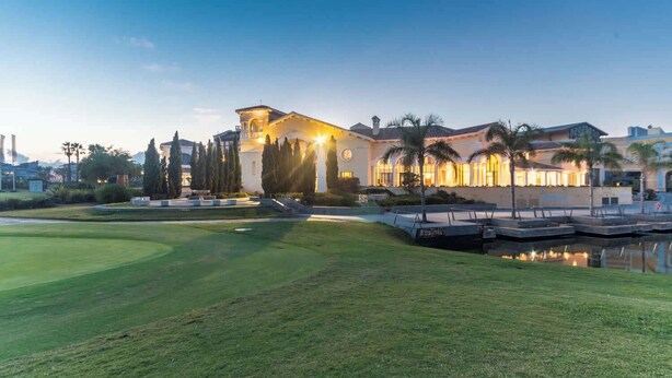 A well-maintained golf course with a clubhouse, palm trees, and a calm water body. - Beautiful apartment PA923LT, Casa Gironi (Murcia)