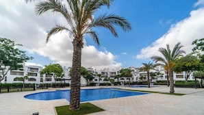 A pool area with palm trees, a clear sky, and white buildings in the background. - Beautiful apartment PA923LT, Casa Gironi (Murcia)