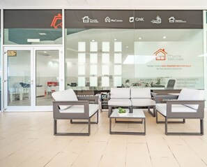 Un espacio de oficina moderno con área de recepción, que incluye un conjunto de sofás y una mesa de centro.