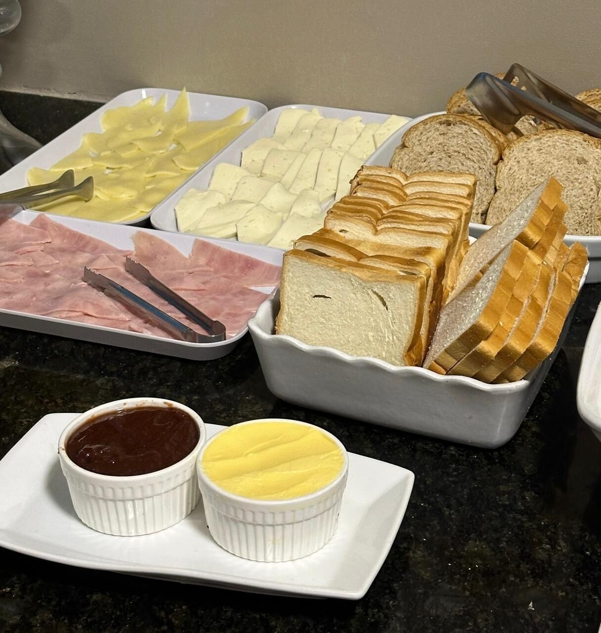 A buffet with sliced meats, cheeses, and bread.