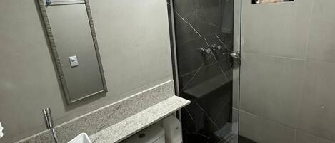 Un bagno moderno con doccia vetrata, lavandino bianco e servizi igienici.