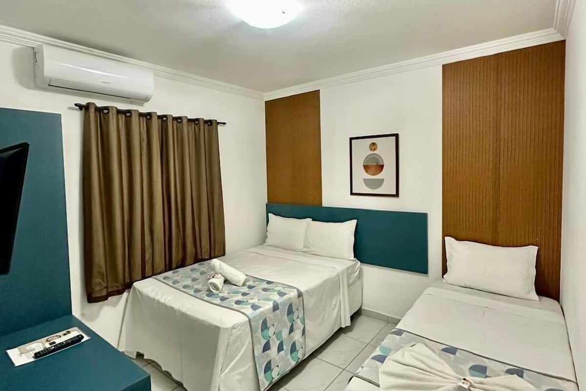 Ein Hotelzimmer mit zwei Betten, einem Fernseher und einer Klimaanlage.