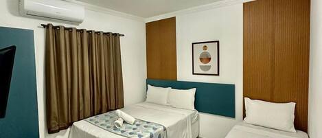 A hotel room with two beds, a TV, and an air conditioning unit.