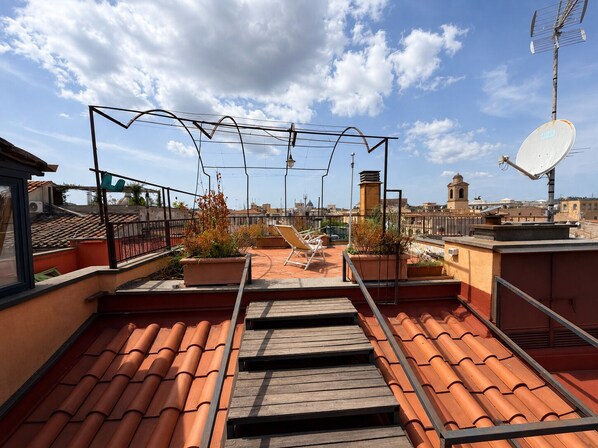 A rooftop terrace with terracotta tiles, a satellite dish, and a view of the cityscape. - Penthouse with Terrace near Pantheon (Roma)