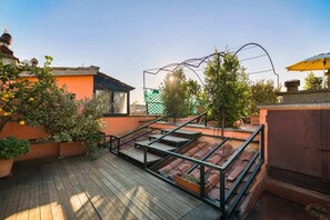 A rooftop terrace with a wooden deck, potted plants, and a metal pergola structure. - Penthouse with Terrace near Pantheon (Roma)