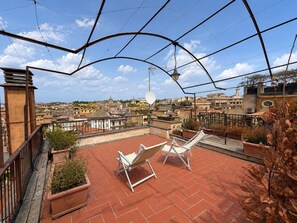 A rooftop terrace with two white lounge chairs, a satellite dish, and a view of a cityscape with historical buildings. - Penthouse with a terrace near the Pantheon (Roma)
