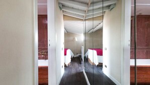 Un couloir étroit aux murs recouverts de miroirs mène à une chambre dotée de deux lits.