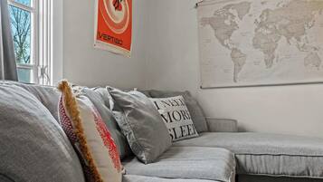 Ein graues Sofa mit Zierkissen, eine Weltkarte an der Wand und ein Plakat mit einer Tänzerin.