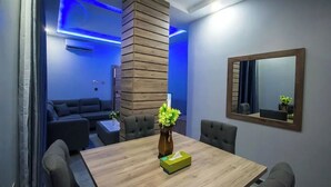 A modern dining area with a wooden table, chairs, and a vase with flowers. - Golden Grand Royale Hotel  (Lokoja)