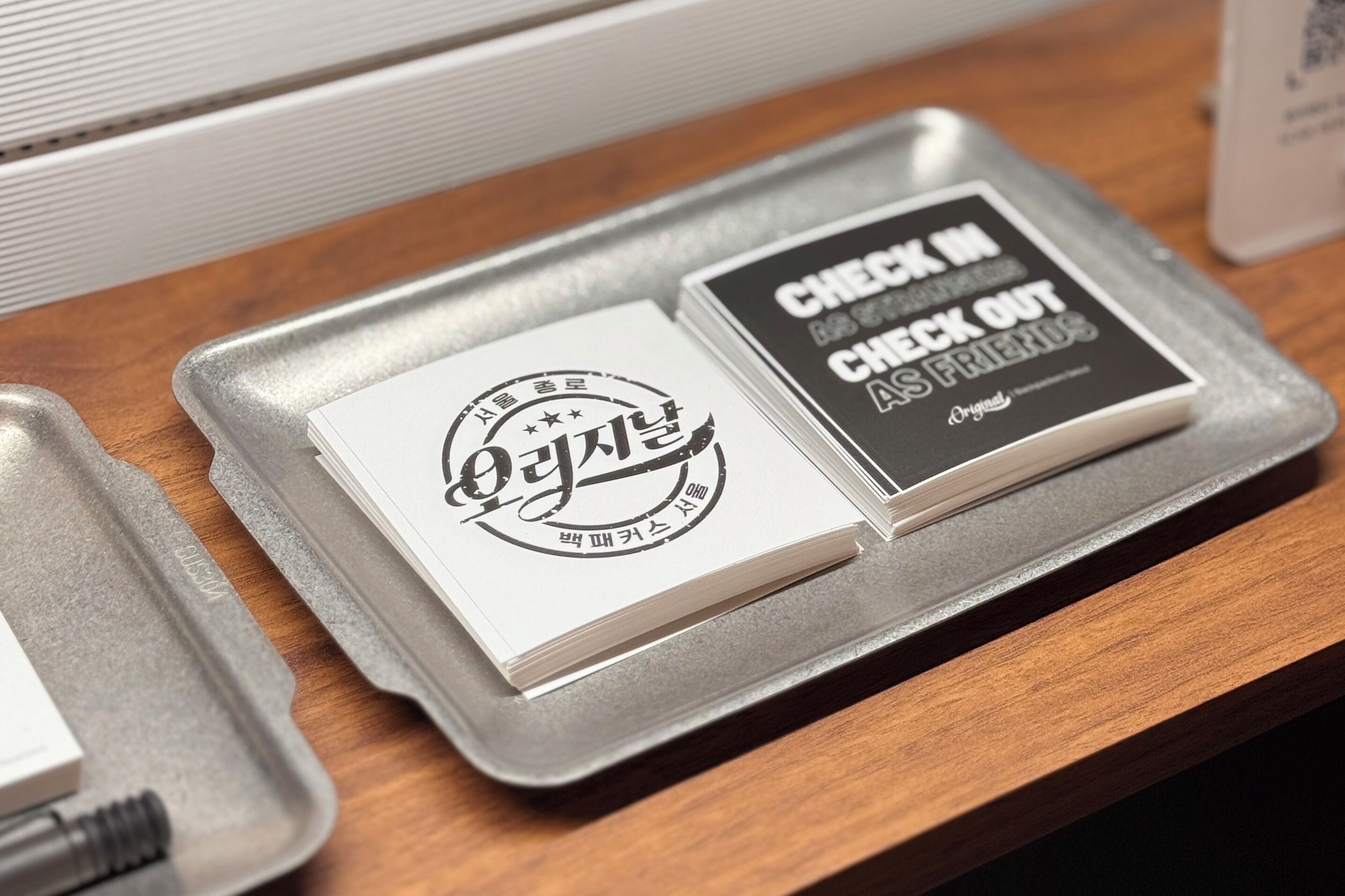 A tray with two business cards on a wooden surface.