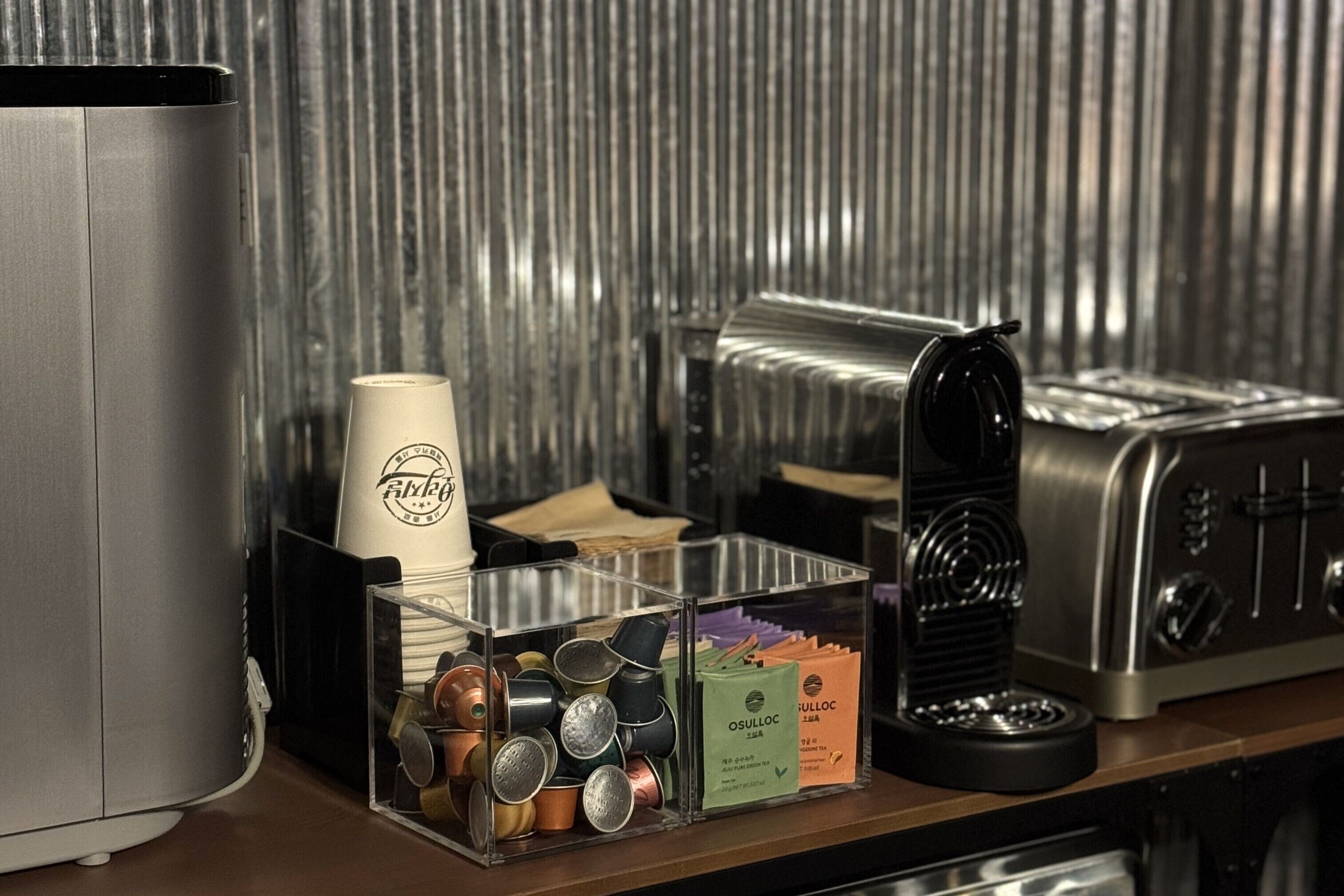 A coffee station with a coffee machine, a cup holder, and a container of tea bags.