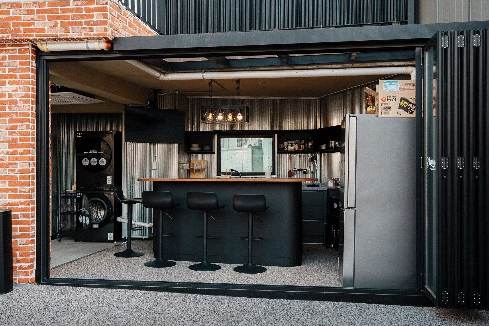 A compact kitchen with a bar area, a washing machine, and a refrigerator.