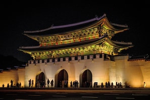 A traditional building with a large entrance and multiple arches, illuminated at night. - Original Backpackers (Seoul)