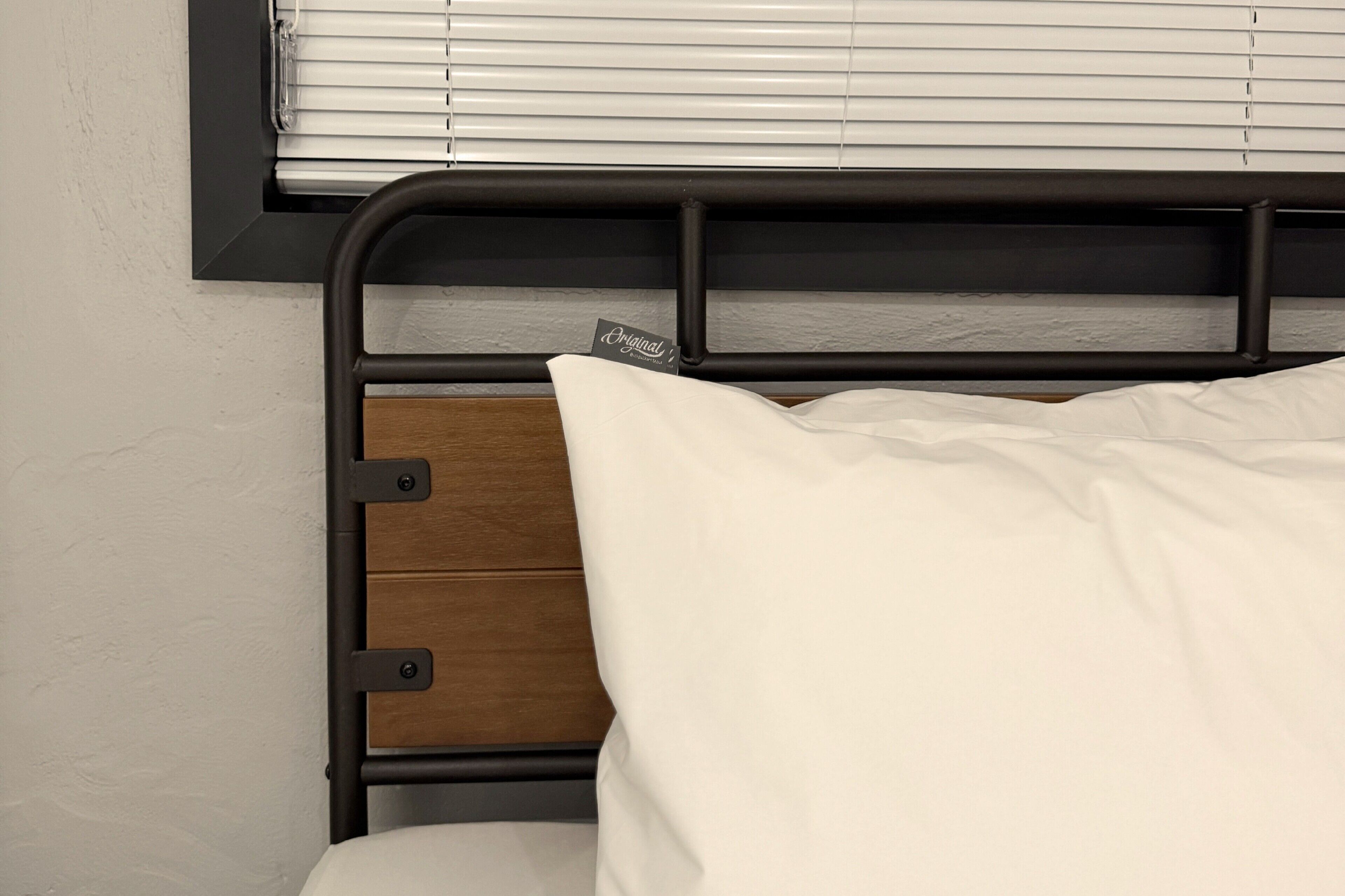 Una cama con cabecera de madera y almohada blanca.
