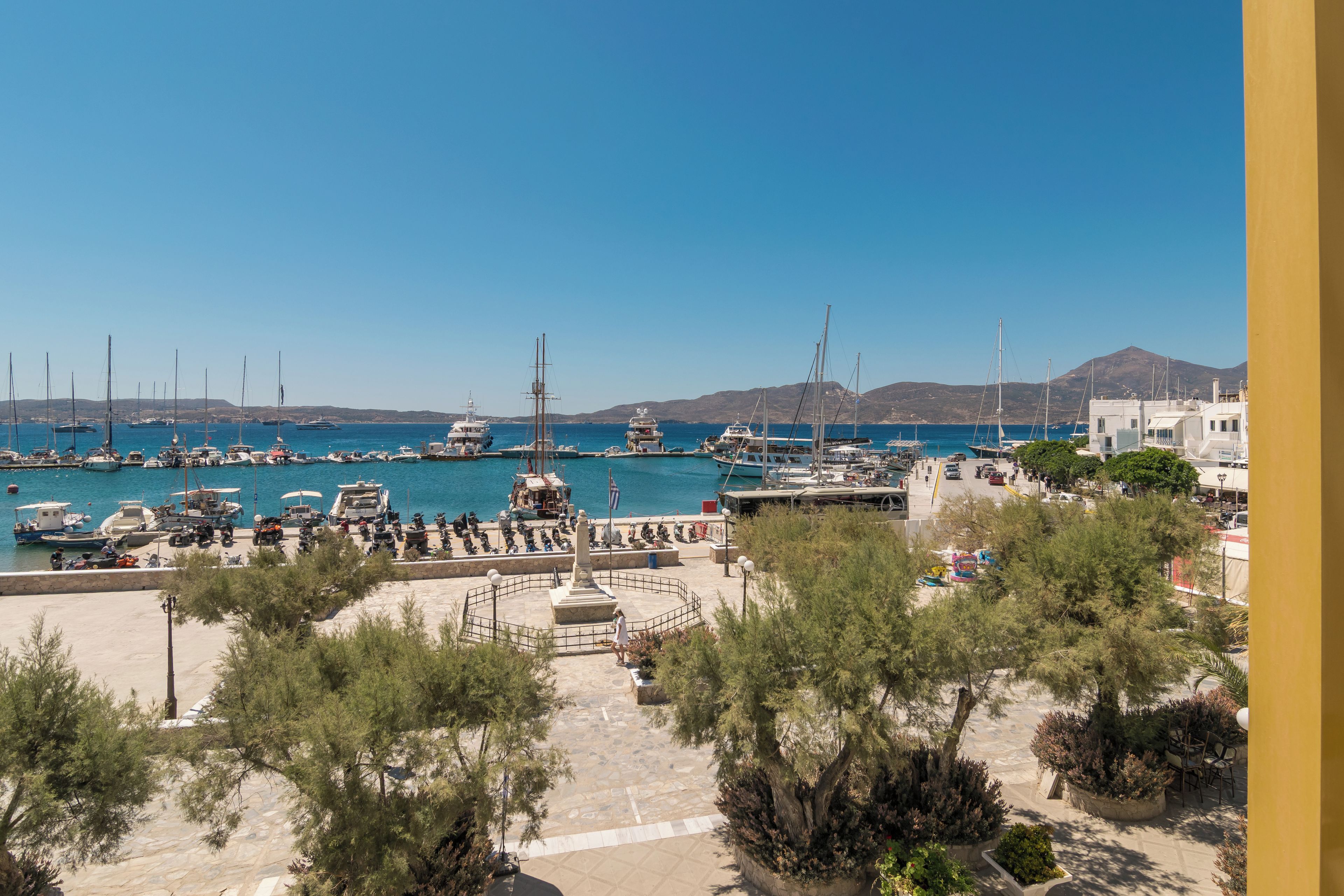 A marina with boats docked, a clear sky, and a mountainous backdrop.