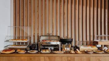 Een buffetopstelling met diverse gerechten, een grill en een koffiecorner.