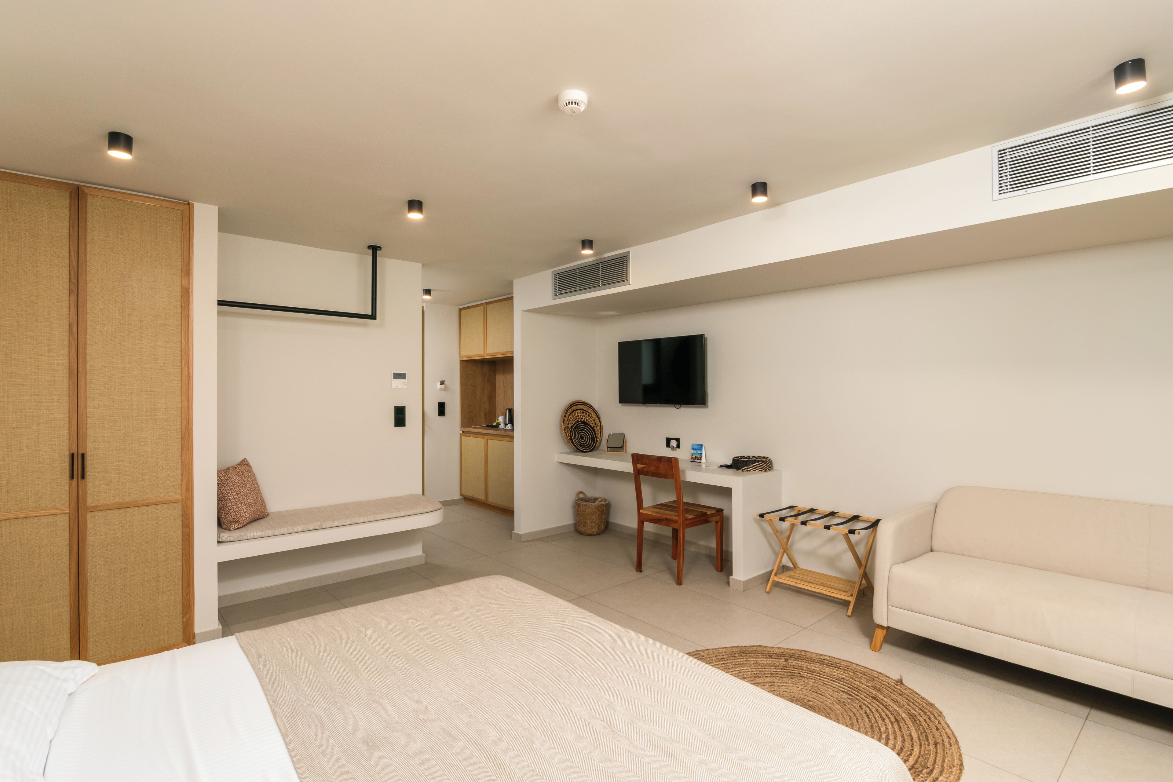 Ein modernes Schlafzimmer mit Bett, Schreibtisch, Fernseher und einer Couch.