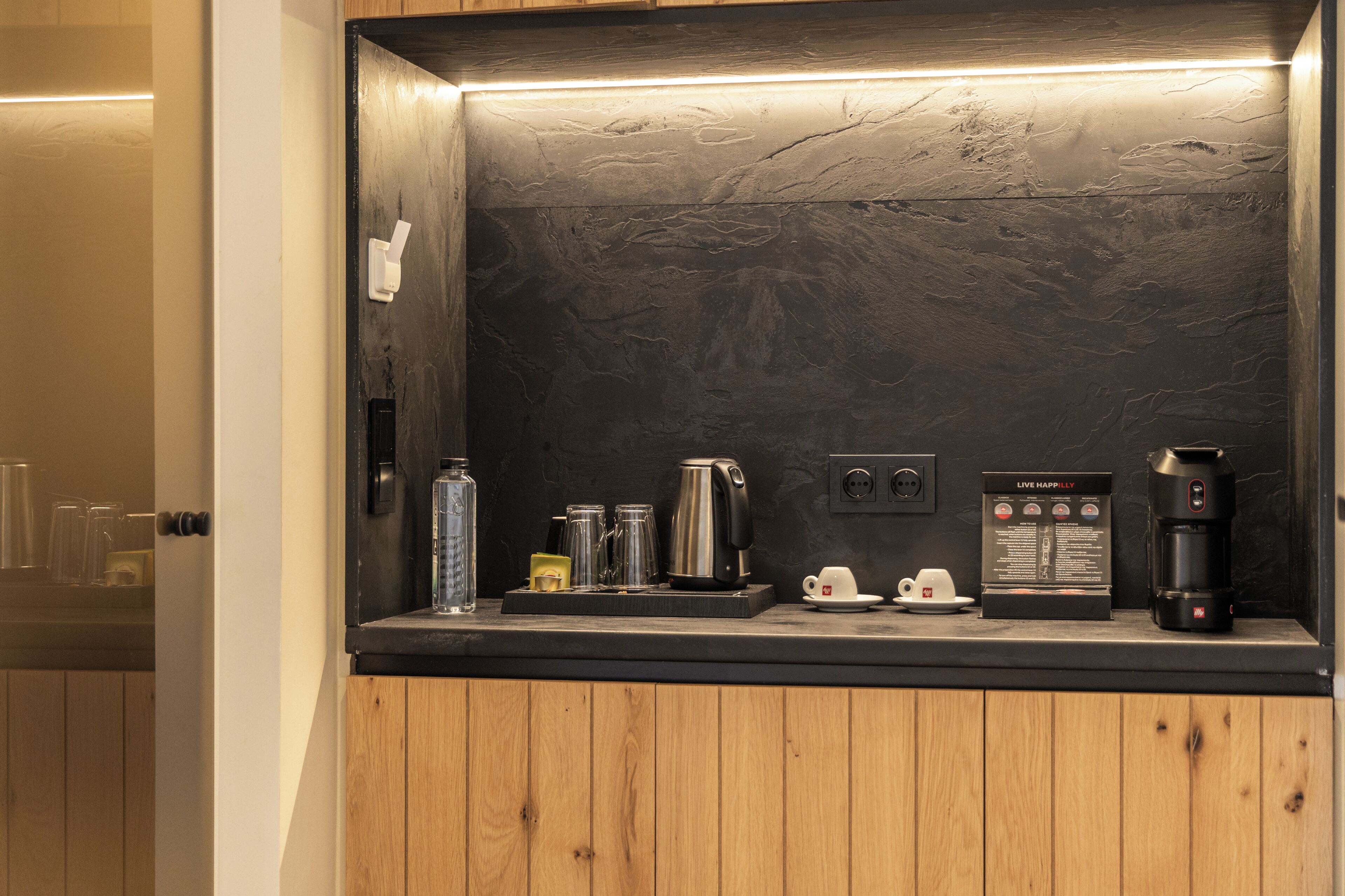 Una cocina moderna con protector de estufa de piedra oscura, armarios de madera y una cafetera.