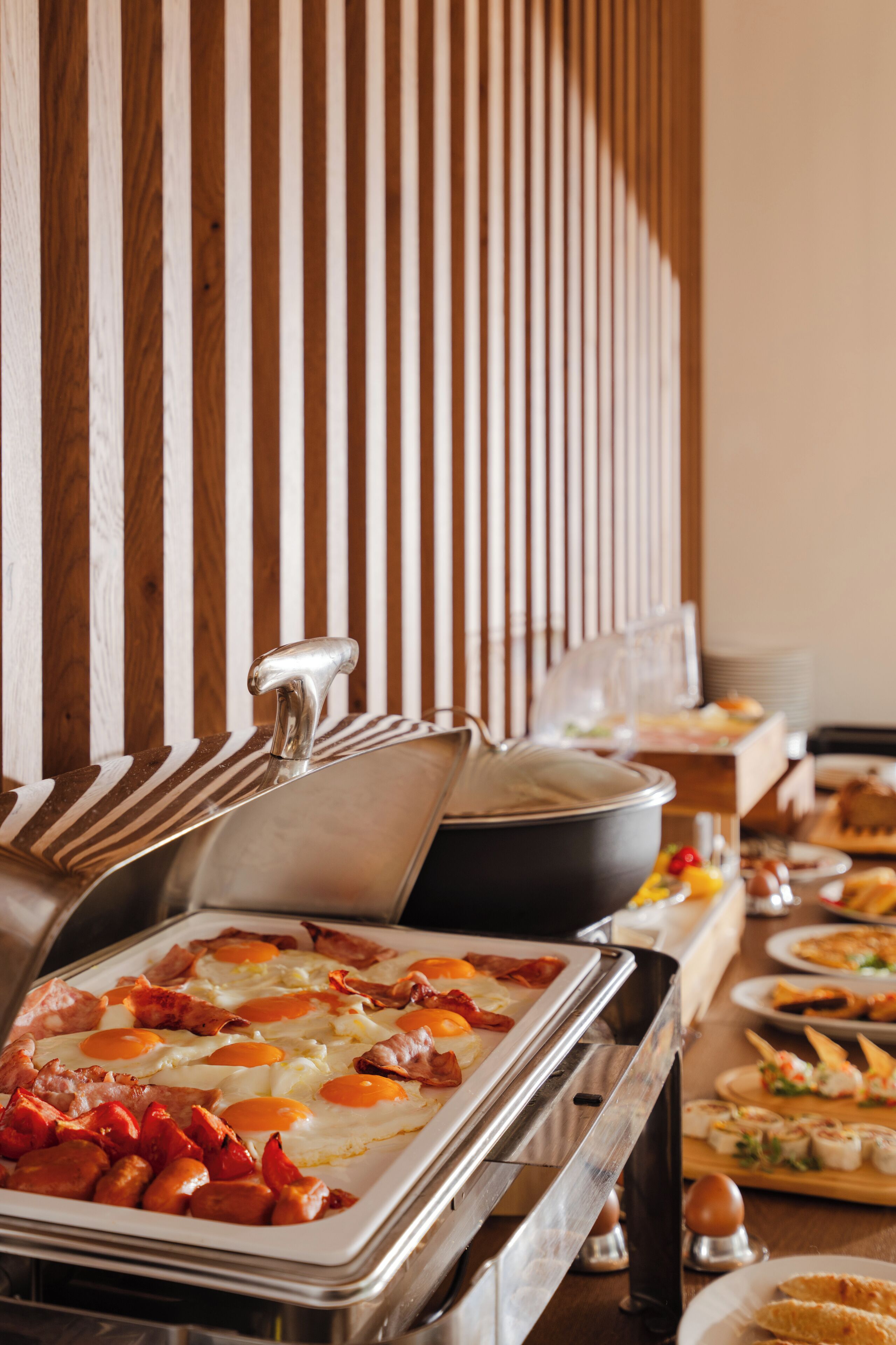 A buffet with various food items including eggs, bacon, and sausages.