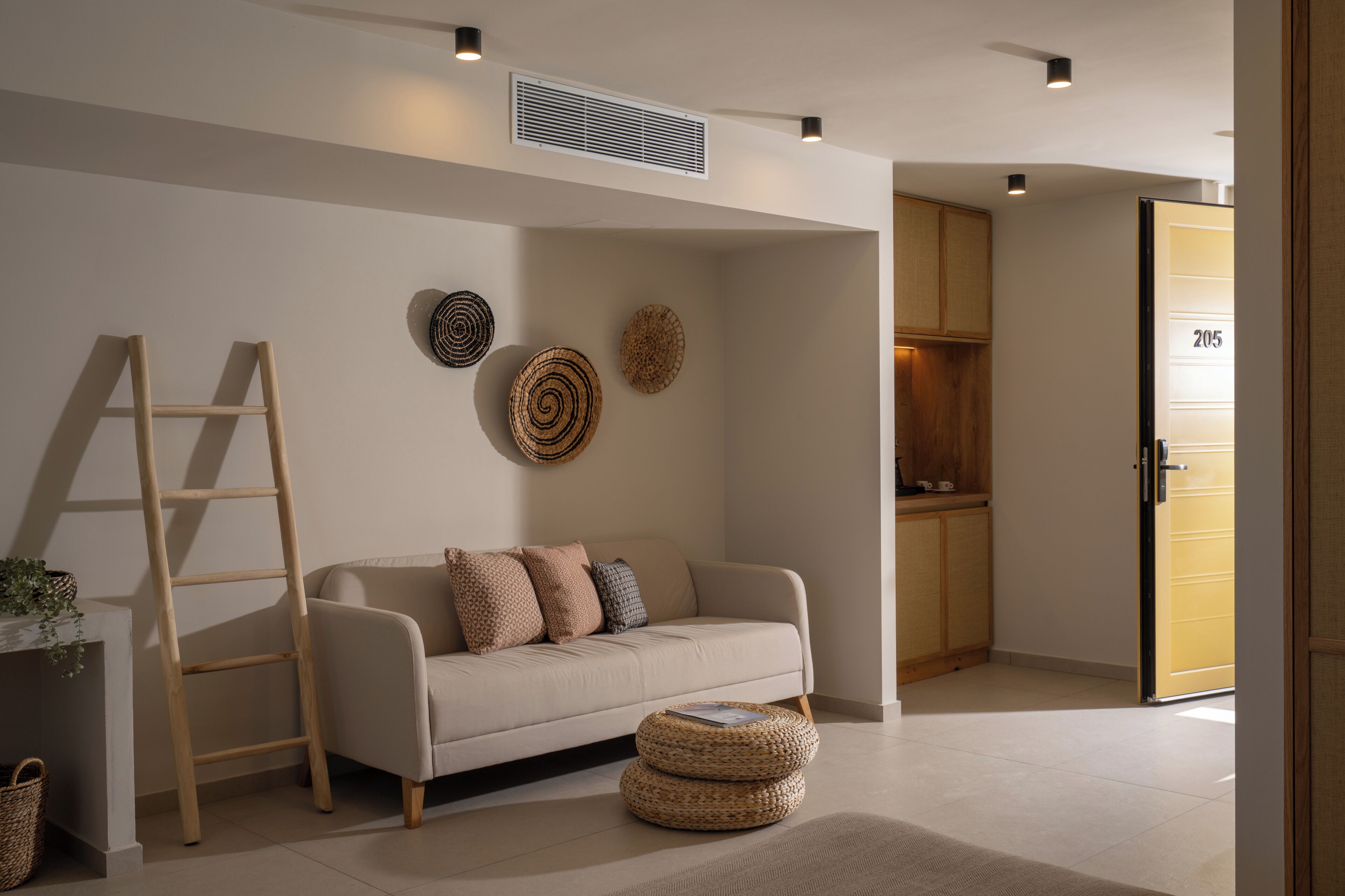 A modern living room with a sofa, a ladder, and woven baskets.