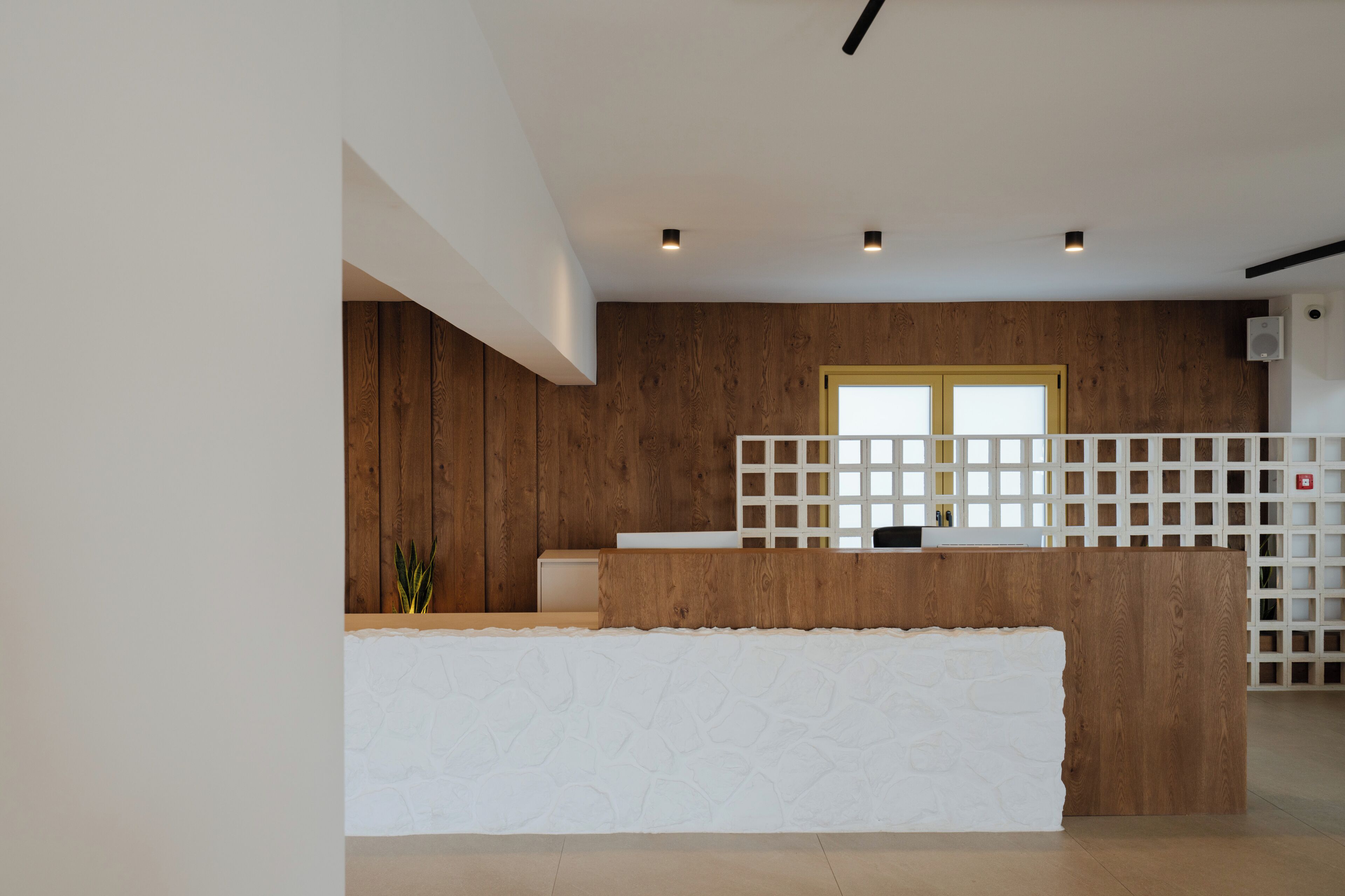 A reception area with a wooden reception desk, a white partition, and a wooden wall.