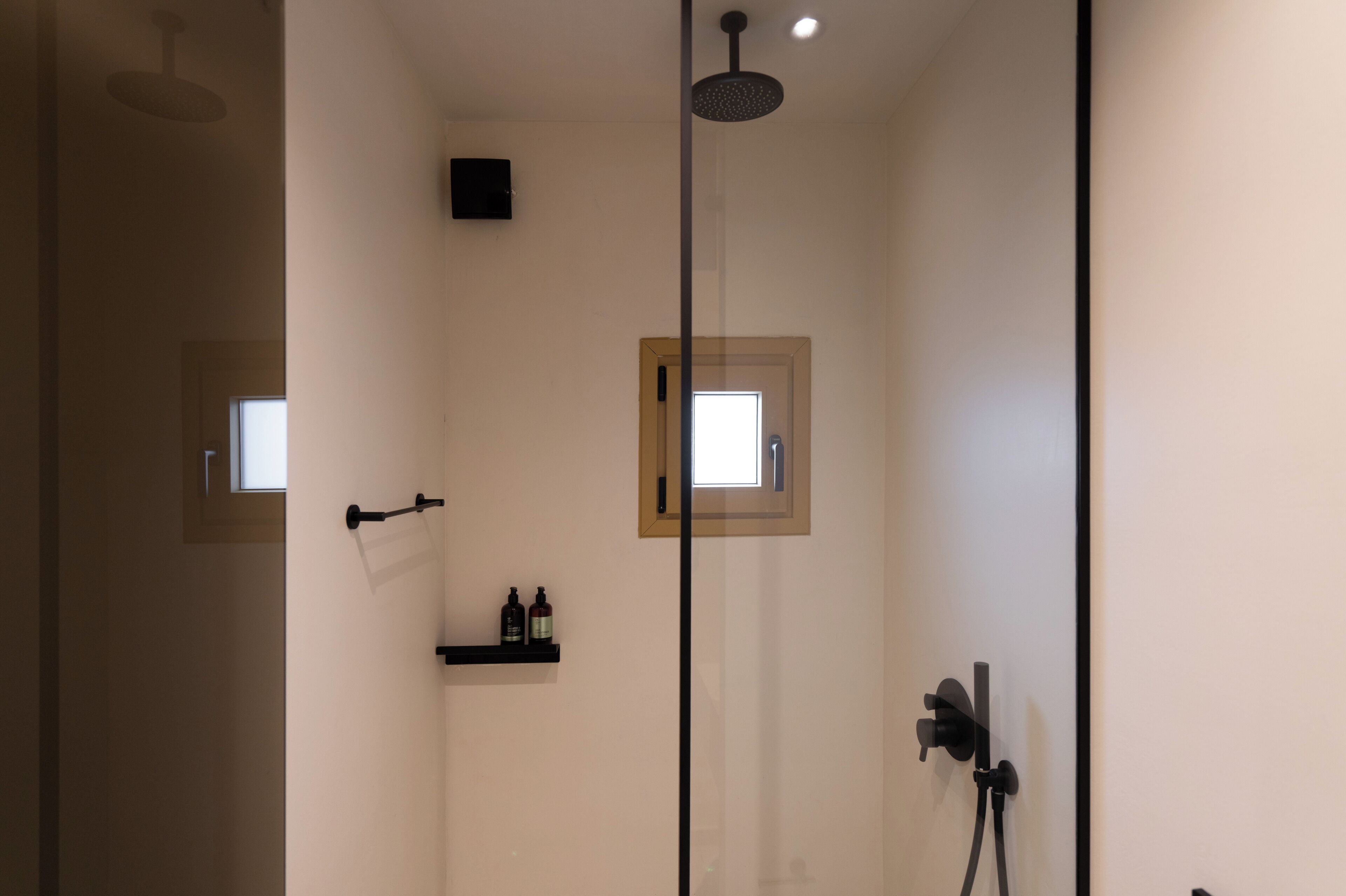 Uma casa de banho moderna com chuveiro, uma janela pequena e um armário com artigos de higiene pessoal.
