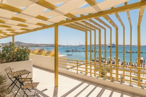A balcony with a view of the sea, featuring a yellow railing and a table with chairs. - Portiani Suites (Milos)
