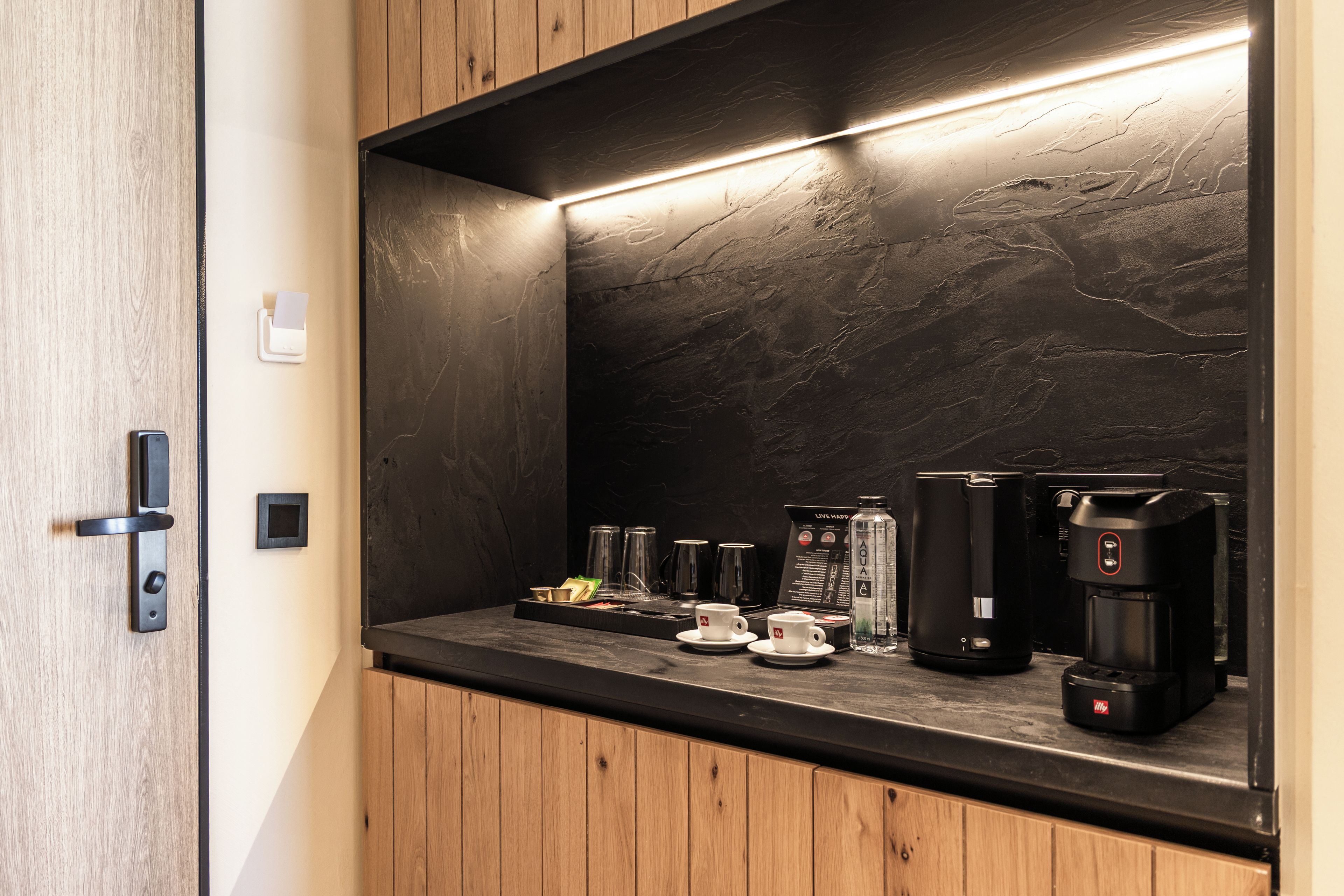 A modern kitchen with a marble backsplash, a coffee machine, and a tea kettle.