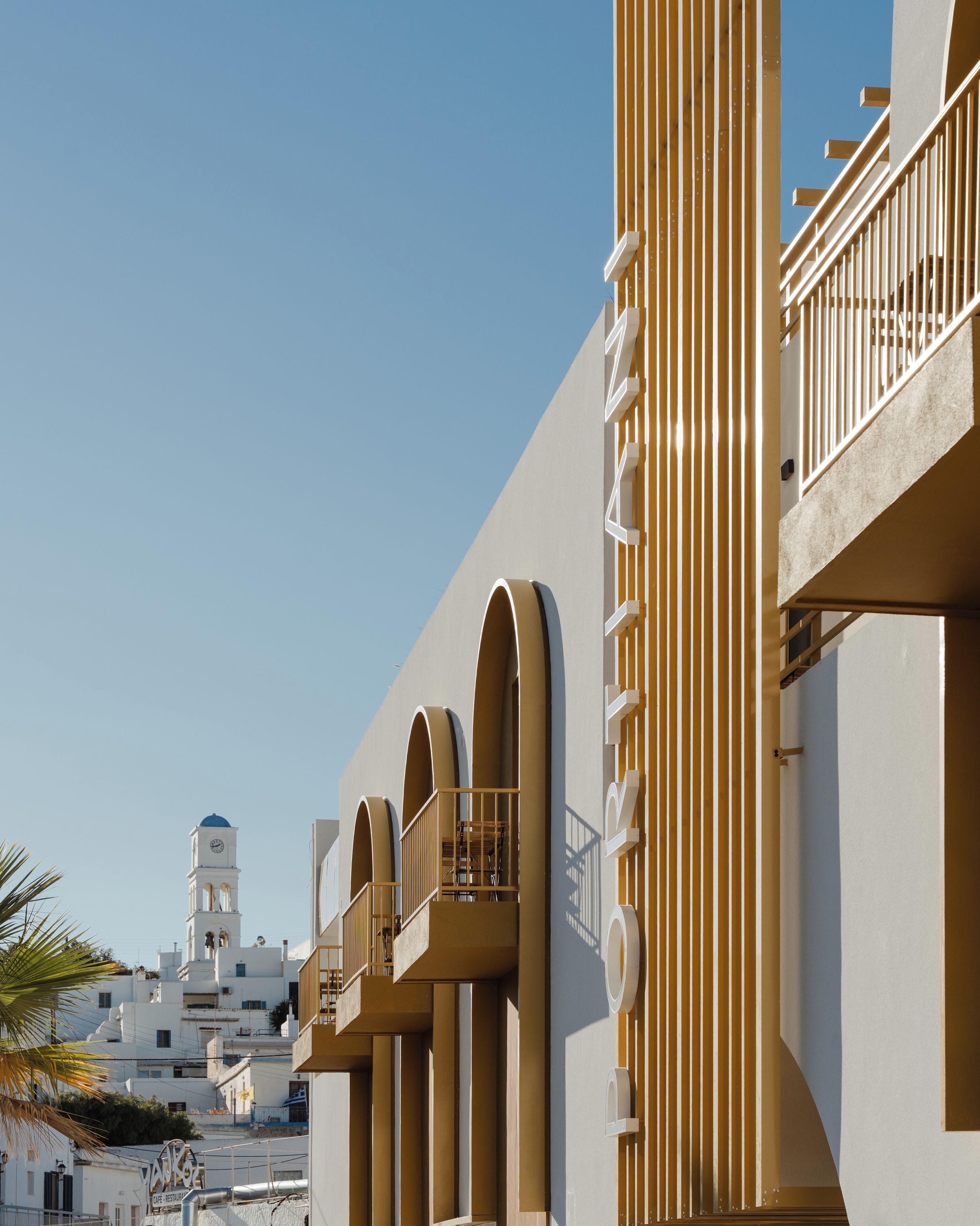 A modern building with balconies and a clock tower in the background.