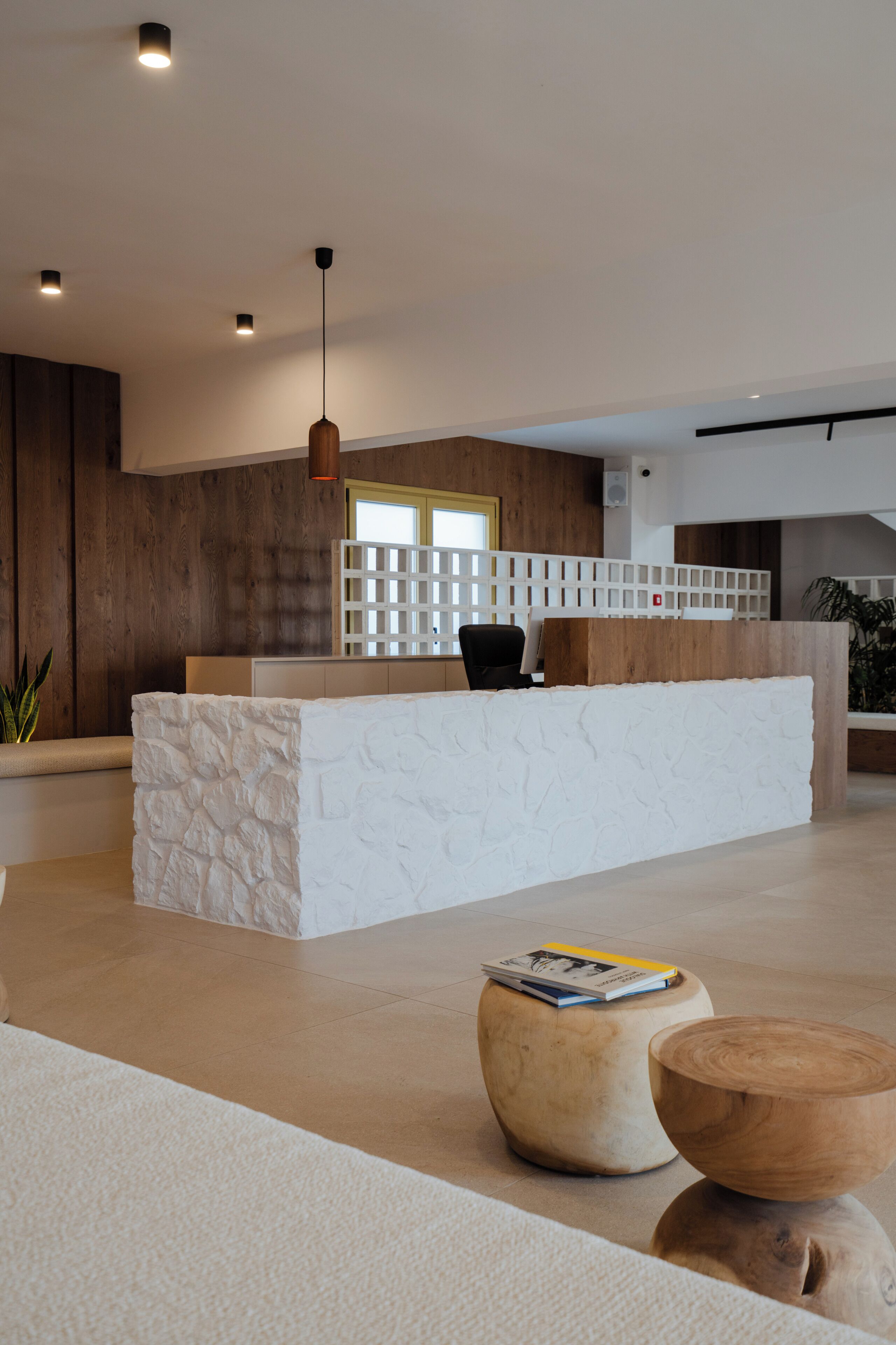 A modern reception area with a white reception desk, a black office chair, and a wooden accent wall.