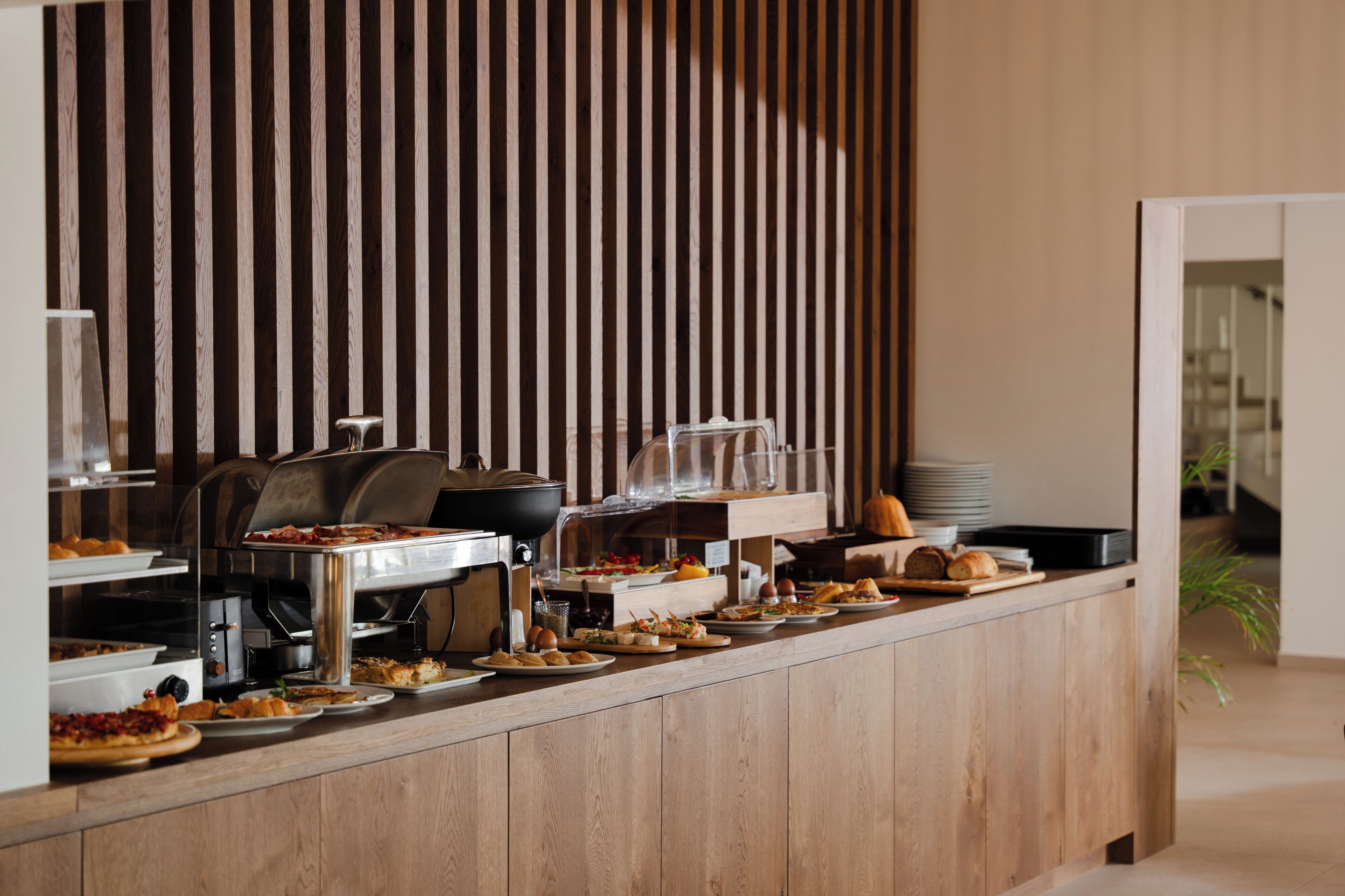 Uma mesa de buffet com diversos alimentos e uma máquina de café.