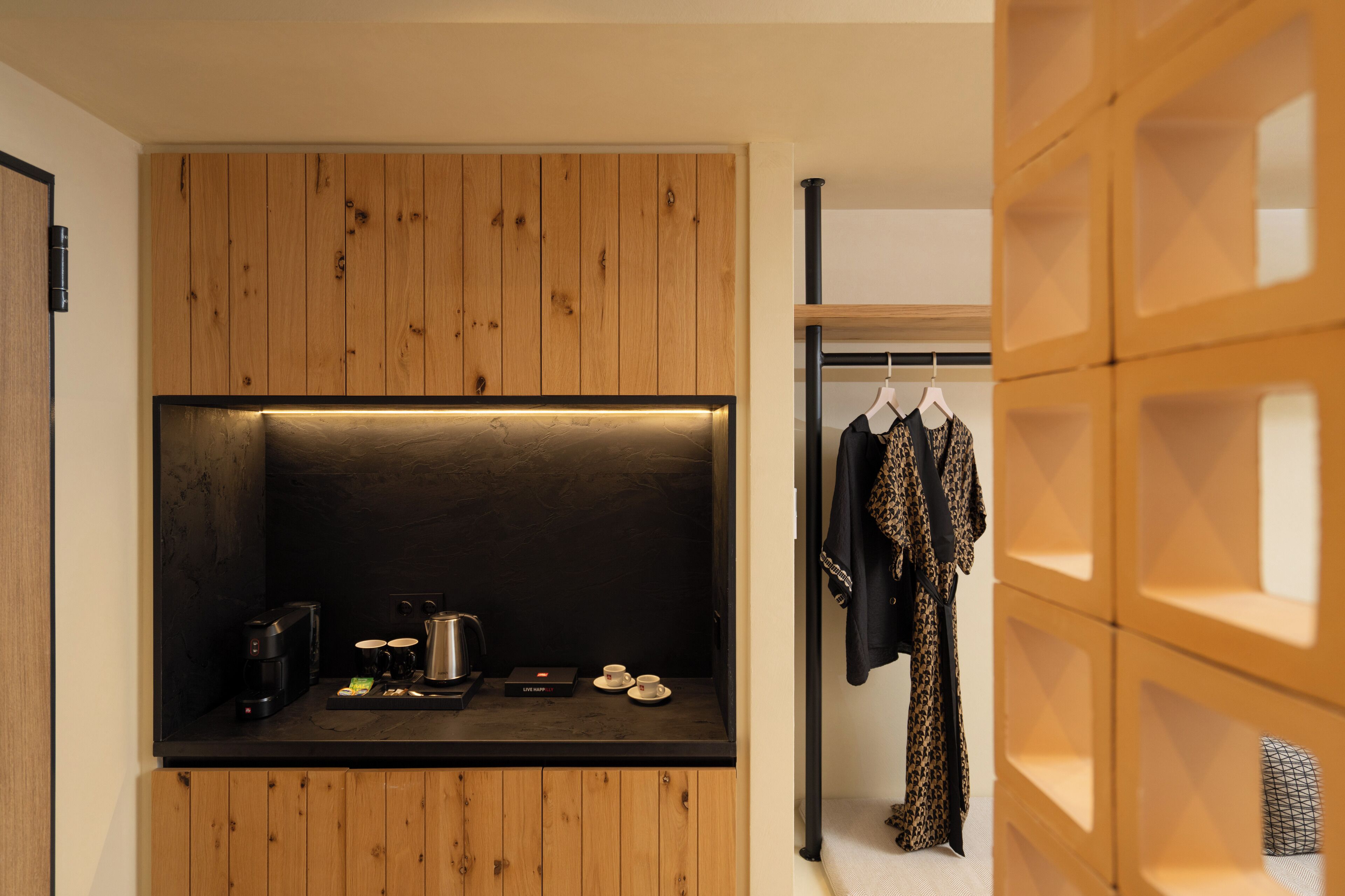 A compact kitchen with wooden cabinetry, a coffee machine, and a kettle.