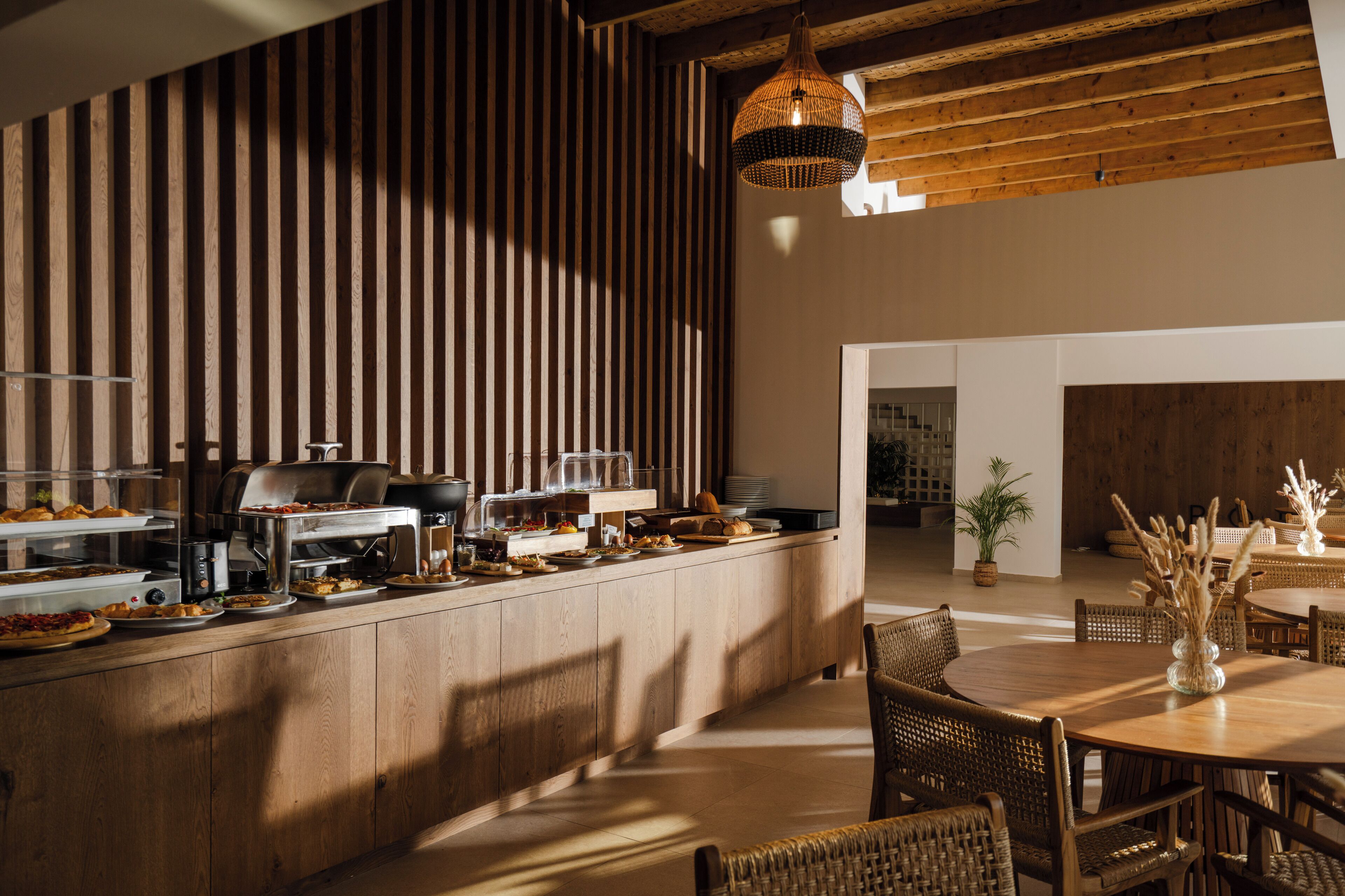 A breakfast bar with various food items and a dining area with wicker chairs and a table.