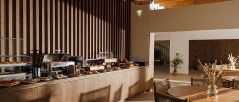 A breakfast bar with various food items and a dining area with wicker chairs and a table.