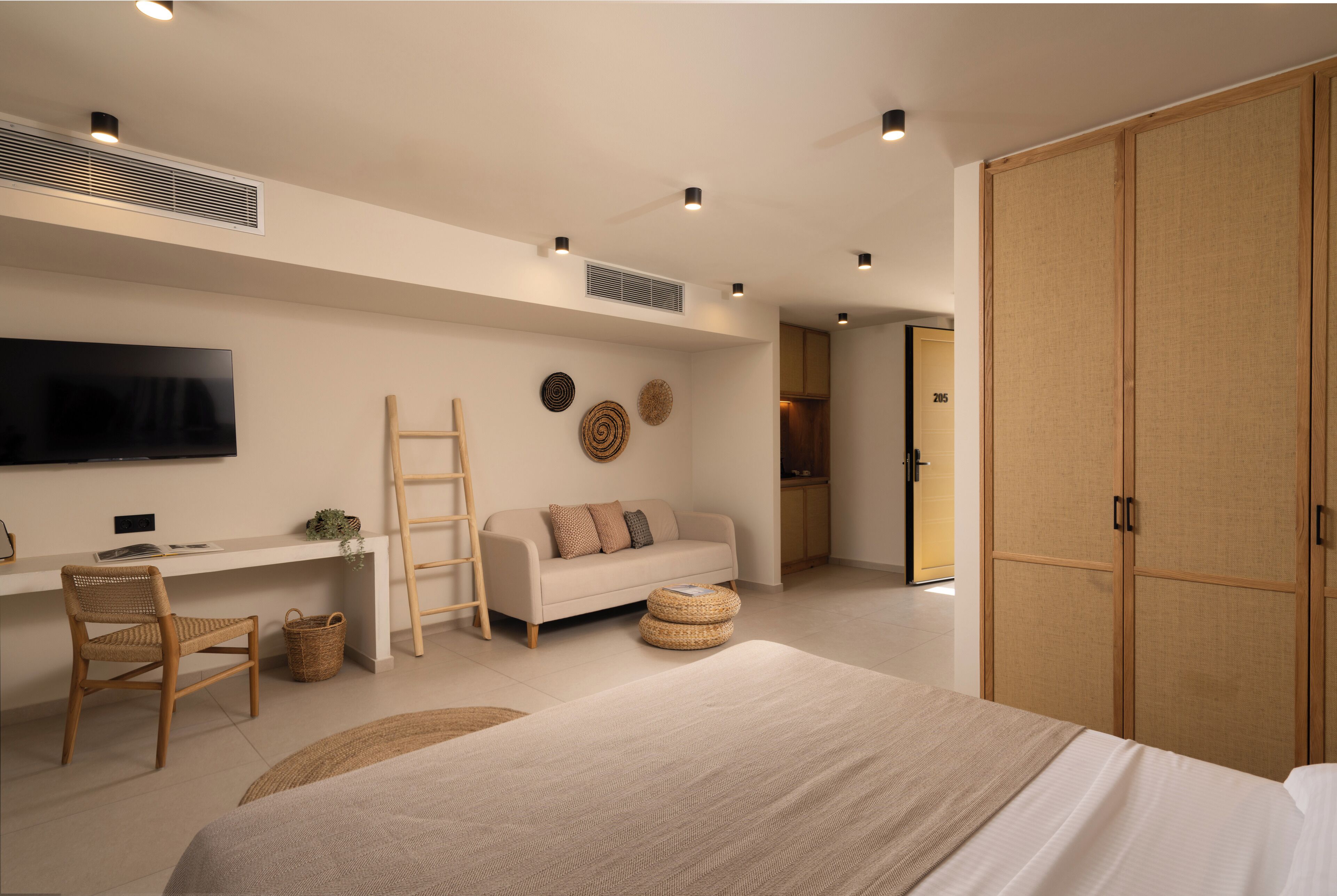 A modern bedroom with a bed, a desk, a TV, and a wardrobe.