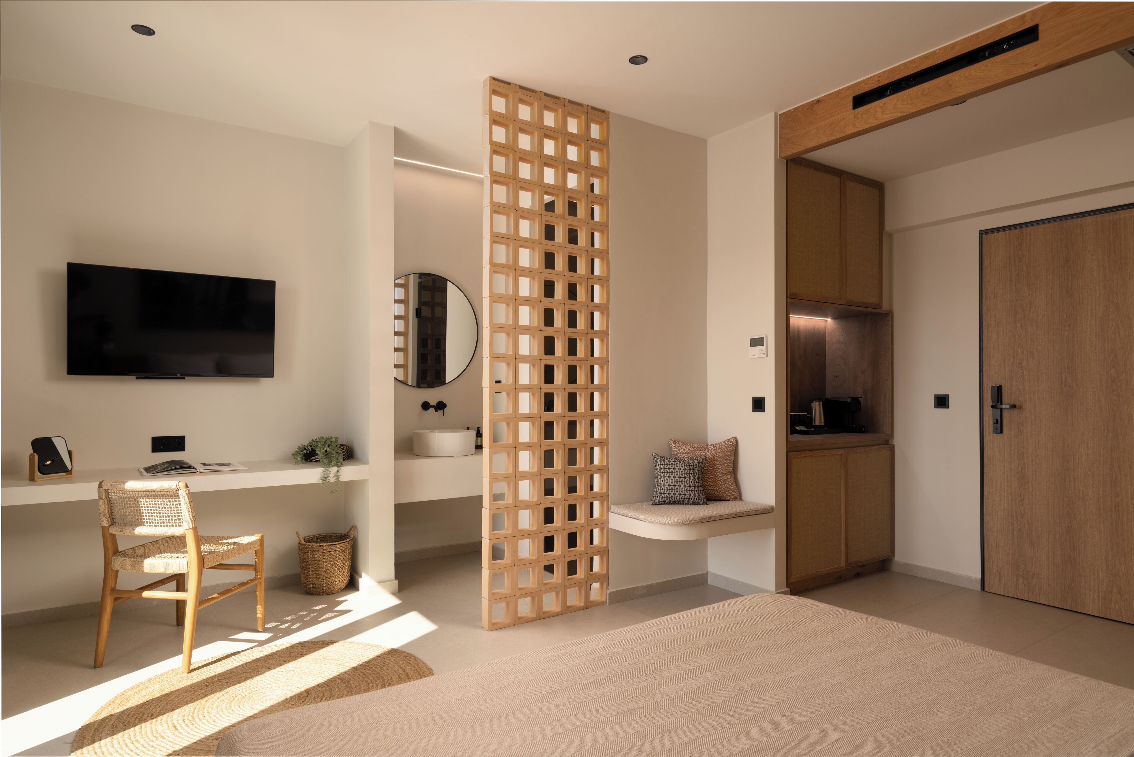 A modern living room with a flat-screen TV, a wooden chair, a woven rug, and a wooden partition.
