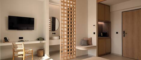 A modern living room with a flat-screen TV, a wooden chair, a woven rug, and a wooden partition.