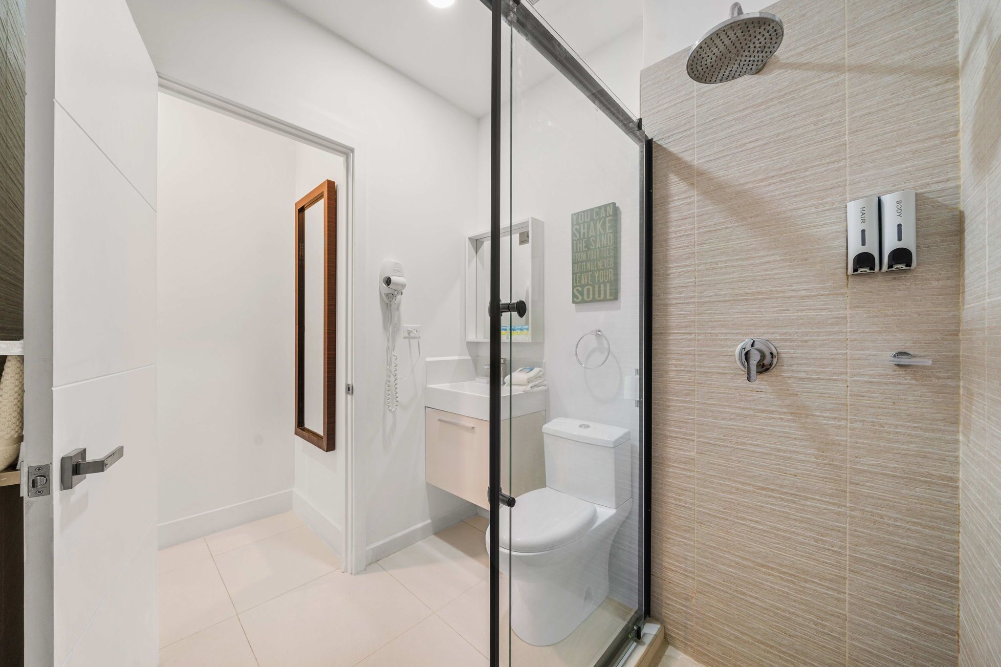 A modern bathroom with a glass shower enclosure, a toilet, and a sink.