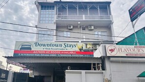 Un immeuble avec une enseigne indiquant « Downtown Stays » et faisant la publicité de chambres avec ou sans climatisation.