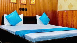 Une chambre d’hôtel avec un mur lambrissé en bois, un lit avec une literie bleue et deux tableaux encadrés accrochés au mur.