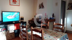 A living room with a TV, wooden chairs, a table with a patterned tablecloth, and a sailboat painting on the wall. - 4-Person Pavilion in Private Park at Jard-sur-Mer (Jard-sur-Mer)