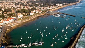 An aerial view of a coastal town with a marina filled with sailboats, a sandy beach, and residential buildings. - 4-Person Pavilion in Private Park at Jard-sur-Mer (Jard-sur-Mer)