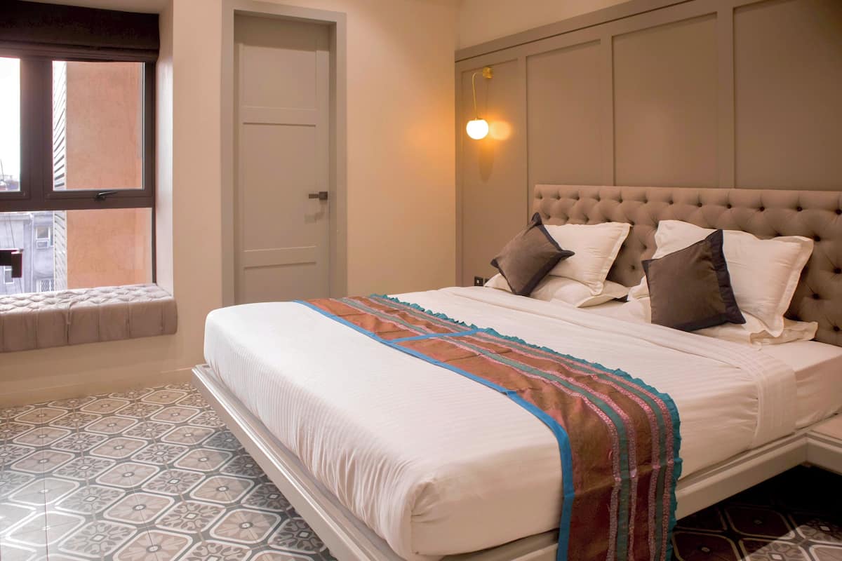 A neatly made bed with a striped blanket, a tufted headboard, and multiple pillows.