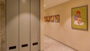 A corridor with a marble floor, a large grey elevator, and a series of framed artworks on the wall. - The 12th Square Saltlake (Bidhannagar)