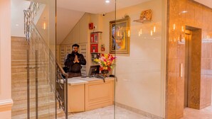 A hotel reception area with a marble floor, a reception desk, a staircase, and a framed picture on the wall. - The 12th Square Saltlake (Bidhannagar)